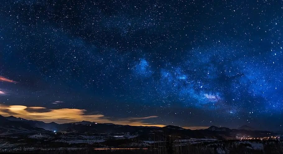 a starry sky over a snowy mountain