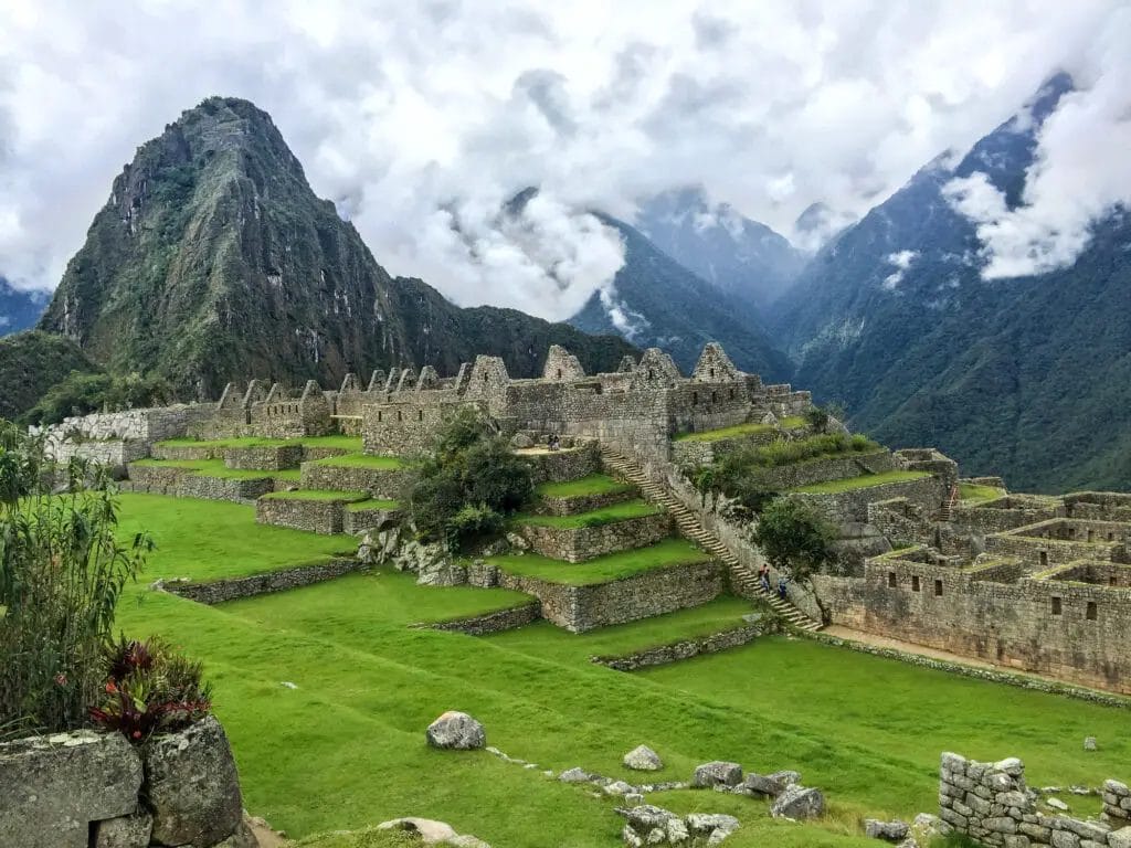A Stone Ruins In A Valley With Machu Picchu In The Background
