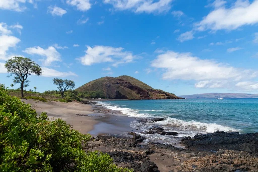 a beach with a hill and water in Maui, Hawaii