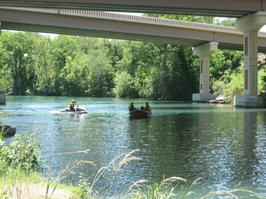 a group of people in boats on a river under a bridge
