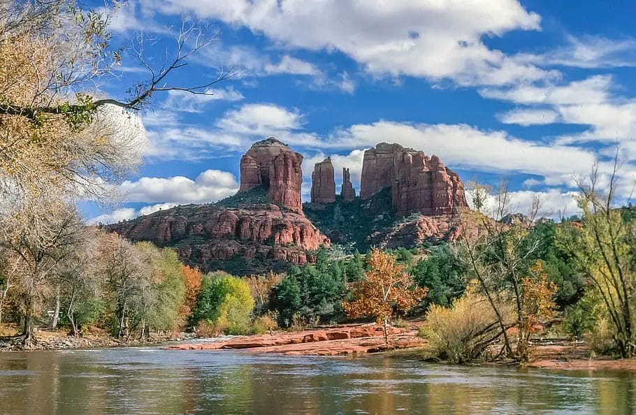 a red rock formation next to a river with Cathedral Rock in the background