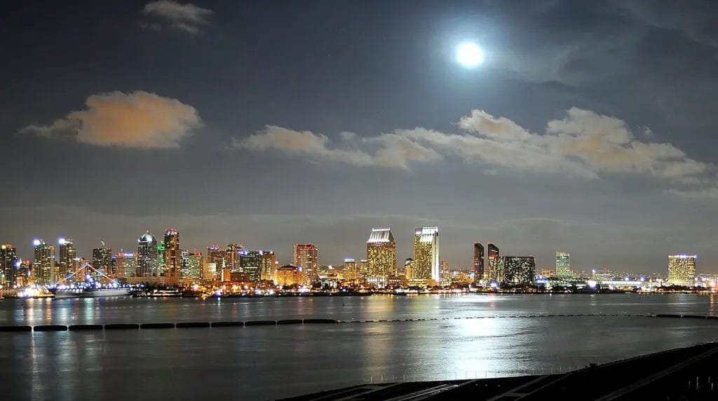 a city skyline at night with the moon in the sky