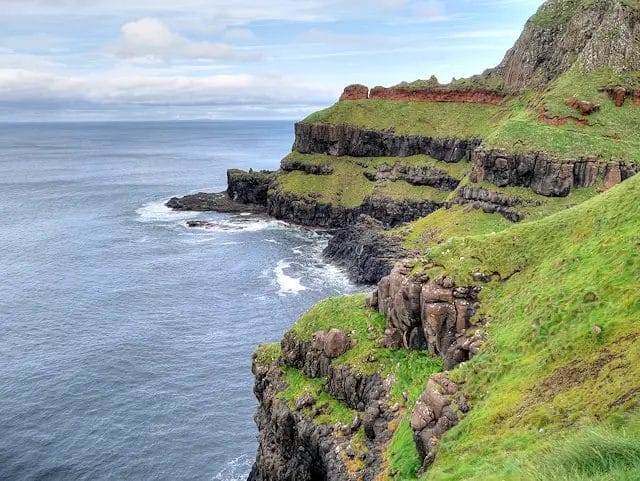 a cliff with grass and rocks by the ocean in Causeway Coast, Co. Antrim