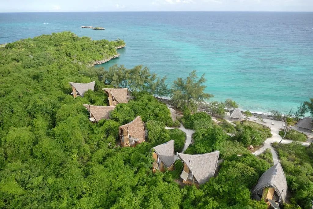 a group of houses surrounded by trees by a body of water in Tanzania